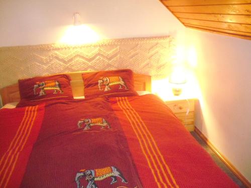 a bedroom with a bed with a red blanket at Topáz Vendégház in Sopron