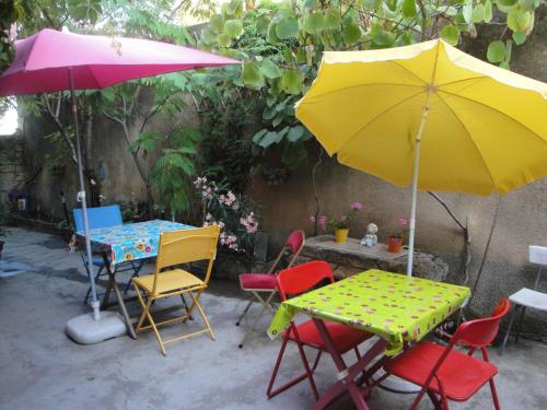a table and chairs with a yellow and pink umbrella at Chez Clairotte in Salinelles