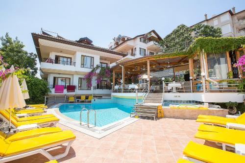 a hotel with a swimming pool and yellow lounge chairs at Villa Sonata in Alanya