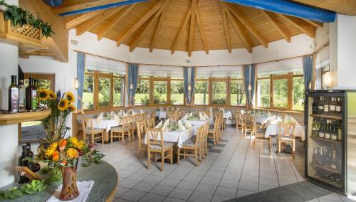 a dining room with tables and chairs and windows at Alpenhotel Badmeister in Flattach