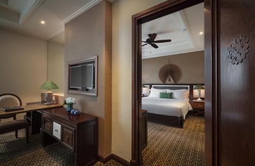 a hotel room with a bed and a desk and a mirror at Ninh Binh Hidden Charm Hotel & Resort in Ninh Binh
