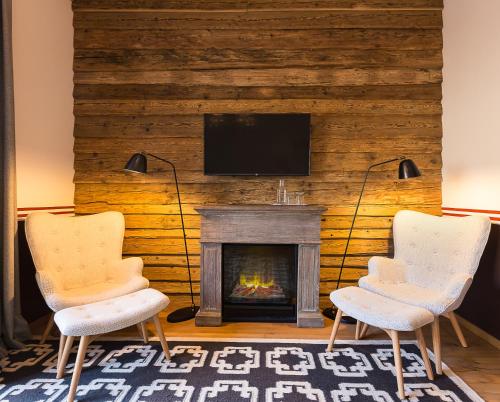 two chairs in front of a fireplace with a tv at House of Hütter - Wachtelhof & SPA in Maria Alm am Steinernen Meer