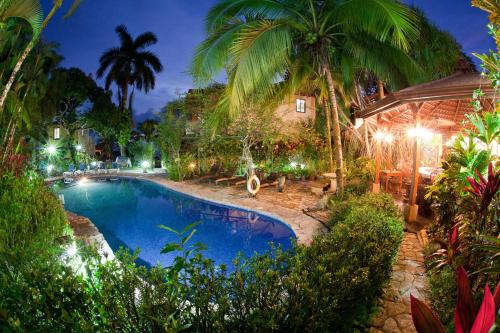 a swimming pool in a resort with palm trees at Hotel Villas Nicolas - Adults Only in Manuel Antonio