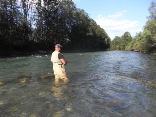 a man is standing in the water with a fishing rod at Ferienwohnung Karin Humer in Bad Ischl