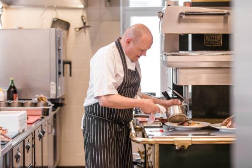a man in a kitchen preparing food in a kitchen at Kasteeltje Hattem in Roermond