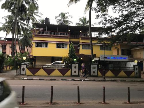 una persona che cammina lungo una strada di fronte a un edificio giallo di Campal Beach Resort a Panaji