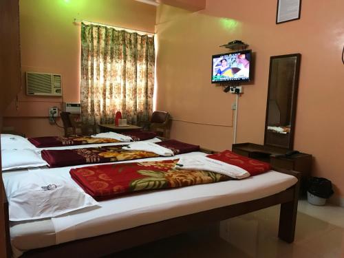Un grupo de camas en una habitación con TV en Campal Beach Resort, en Panaji
