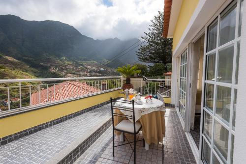 a balcony with a table and a view of the mountains at Terrace View House (Cantinho das Feiteiras) in São Vicente
