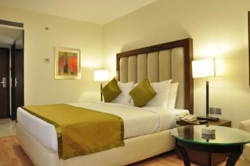 um quarto de hotel com uma cama grande e uma mesa em Adarsh Hamilton em Bangalore