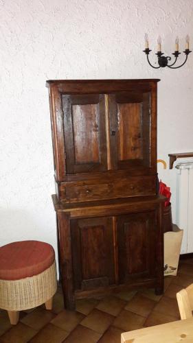 a large wooden cabinet with a stool in a room at Rifugio tra i monti in Alagna Valsesia