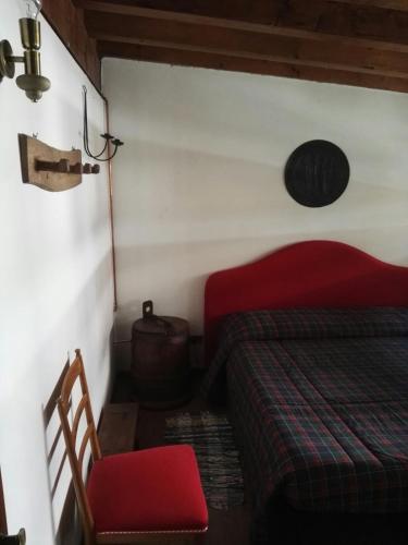 a bedroom with a red bed and a red chair at Rifugio tra i monti in Alagna Valsesia