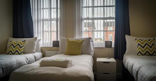 a room with two beds and two windows at The Racecourse Gathering in Chester