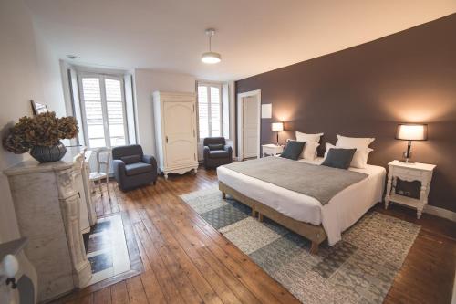 a bedroom with a large bed and two chairs at Le Relais de l'endormie in Nogent-sur-Seine