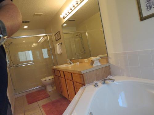 a bathroom with a tub and a sink and a toilet at 3 Bedroom Standard Davenport Home FL 33897 in Orlando
