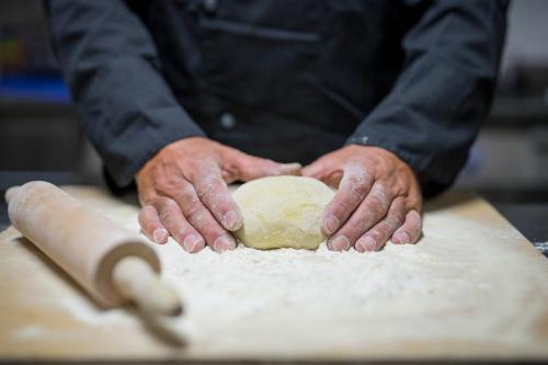 a man is kneading a dough on a table at La Gustea Hotel & Cucina in Sarteano