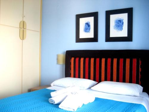 a bed with two pillows and two pictures on the wall at Corina Apartments in Sitia