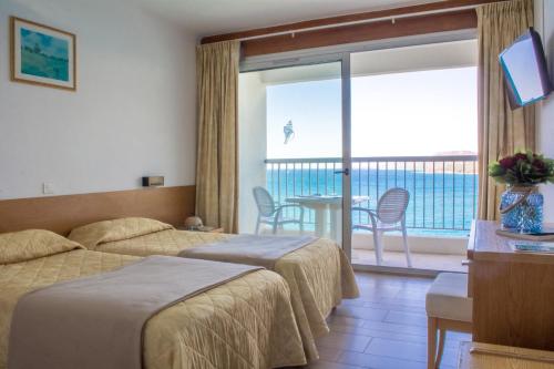 Una habitación de hotel con dos camas y balcón. en Hotel Roc E Mare, en Propriano