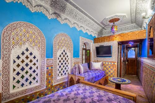 a living room with a purple couch and a tv at Riad Hiba in Meknès