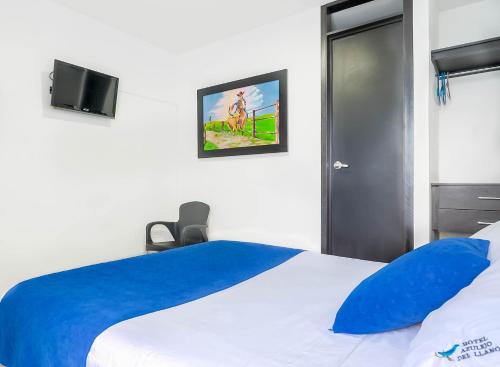 a bedroom with a blue and white bed and a tv at Hotel Azulejo del Llano in Yopal