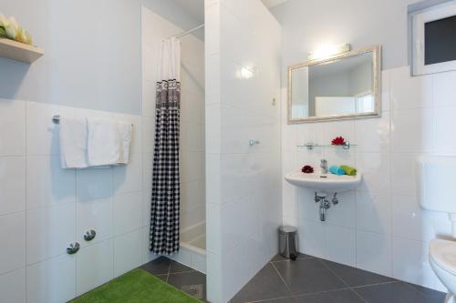 een witte badkamer met een wastafel en een douche bij Apartment Kyra in Lovran