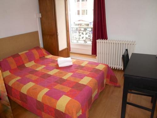 a bedroom with a bed and a table and a window at Hôtel Chateaubriand in Dijon