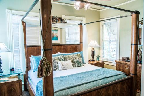 a bedroom with a four poster bed and windows at Peace & Plenty Inn Bed and Breakfast Downtown St Augustine-Adults Only in Saint Augustine