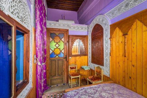 a bedroom with a bed and a wooden door at Riad Hiba in Meknès