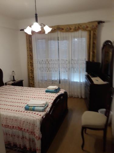 a bedroom with a bed and a chair and a window at Apartamento do Paim in Ponta Delgada