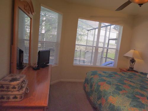 a bedroom with a bed and a tv and two windows at Formosa Garden Pool Home in Orlando