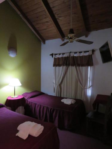 Un dormitorio con dos camas y un ventilador de techo. en Hotel Jardin del Lago, en Villa Carlos Paz