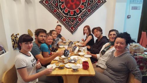 a group of people sitting around a wooden table at Amir Hostel in Samarkand