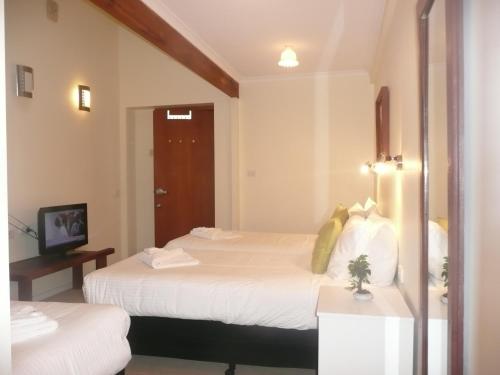 a hotel room with two beds and a television at Getaway Inn Boutique Guest house in Nulkaba