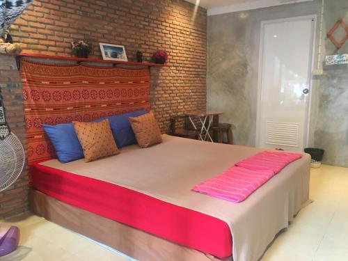 1 dormitorio con 1 cama grande y pared de ladrillo en Just Chill Inn, en Chiang Mai