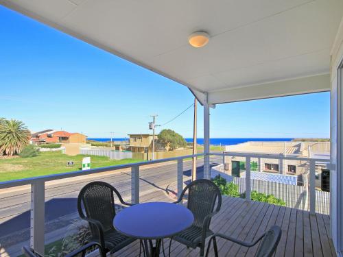 a balcony with a table and chairs and the ocean at Sunset at Snapper Point - Aldinga Beach - C21 SouthCoast Holidays in Aldinga Beach