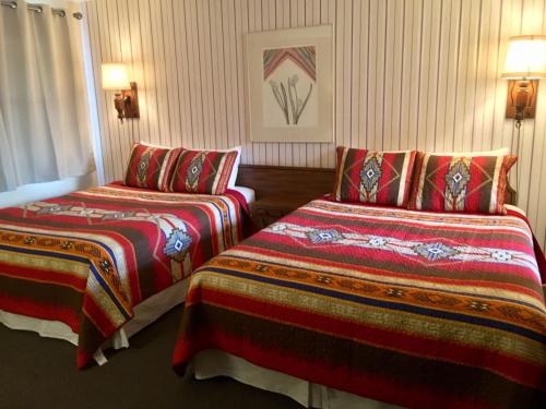 Habitación de hotel con 2 camas y mantas coloridas en Sharon Motel, en Wells