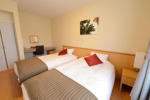 um quarto de hotel com duas camas e uma secretária em Le Nessa Jyogasaki em Ito