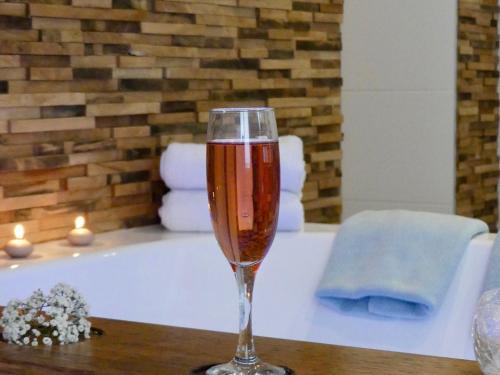a glass of wine sitting on a table in a bath tub at Entre Nous - La Poste in Saumur