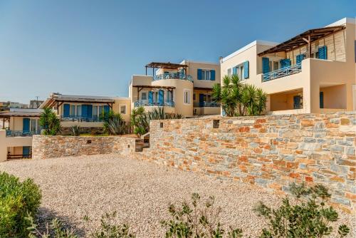 eine Steinmauer mit Häusern im Hintergrund in der Unterkunft Sunrise Beach Suites in Azolimnos