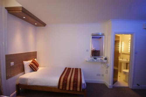 a hotel room with a bed and a mirror at Abbey Court Hotel - Hyde Park in London