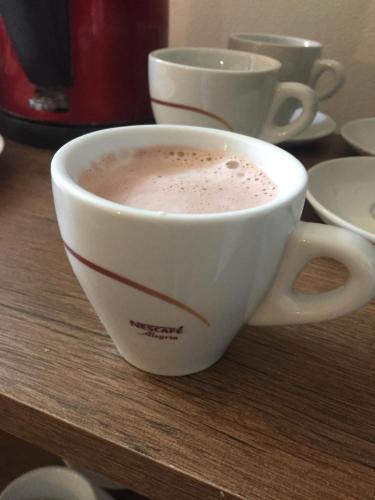 a cup of coffee sitting on a wooden table at Penzion Ema B&B in Prostějov