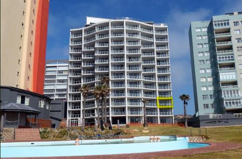 a large white building with palm trees in front of it at Beach Club Unit 207 in Mossel Bay