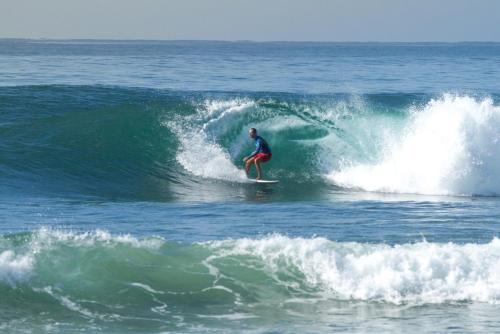 a man riding a wave on a surfboard in the ocean at Midigama Holiday Inn in Midigama