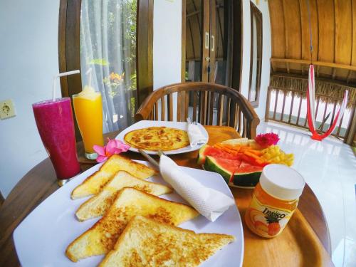 a table with a plate of toast and a plate of food at Ina Gili Guesthouse in Gili Air