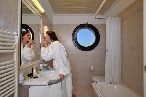 a woman standing in a bathroom brushing her teeth at Hotel Bel Sit in Senigallia
