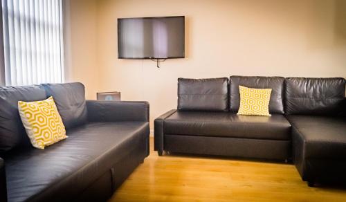 a living room with two leather couches and a flat screen tv at The City Walls Gathering in Chester