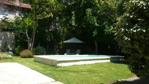 a swimming pool in a yard with an umbrella at L'Observance Bed & Breakfast in Avignon