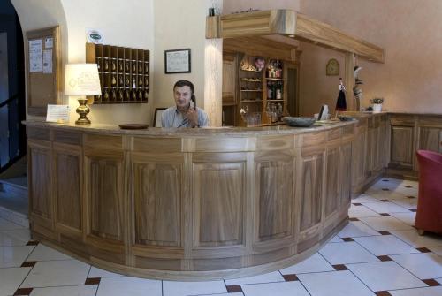 un hombre sentado en un gran bar de madera en un pub en Albergo Italia, en Varallo