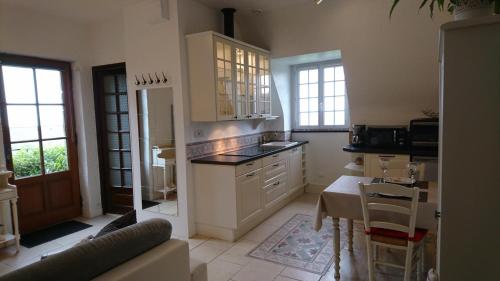 une cuisine avec des armoires blanches et une table à l'intérieur dans l'établissement Appartement vue panoramique sur baie de Morlaix, à Roscoff