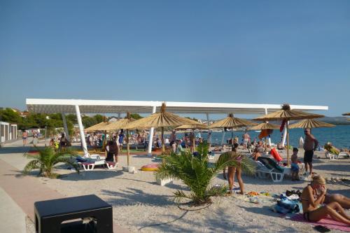 eine Menschenmenge an einem Strand mit Sonnenschirmen in der Unterkunft Apartment Jevic in Raslina