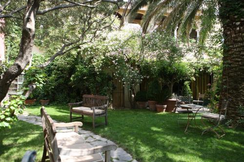 a garden with benches and tables and trees at Jardins Secrets in Nîmes